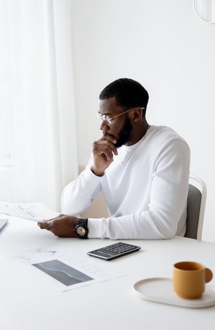 Services Man analyzing documents in a modern workspace with a calculator and coffee
