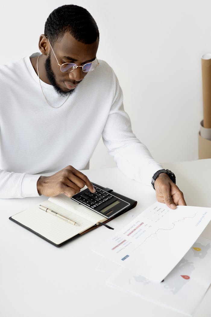 Services Professional analyzing documents and using a calculator at an office desk.